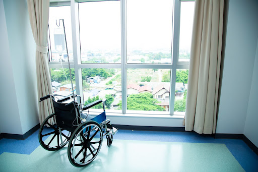 Wheelchair by itself facing a window looking outside. 